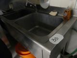 a stainless steel sink in a kitchen with a sign on it