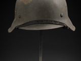un vieux casque posé sur un support, sur fond noir