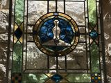 a stained glass window in the corner of a stone wall