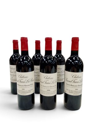 quatre bouteilles de vin rouge sont alignées sur une surface blanche