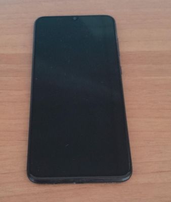 a close up of a cell phone sitting on a wooden table