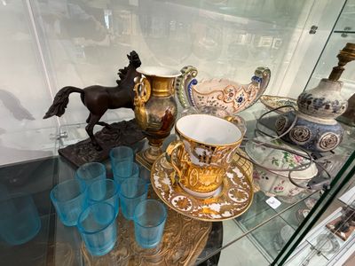 une vitrine en verre contenant une figurine de cheval ainsi qu'une tasse et une soucoupe
