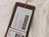 the label of a white dress is attached to a brown tag