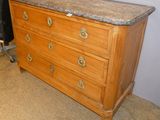 a dresser with a marble top and a chair in the background