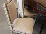 several chairs and a table in a room with a lot of furniture in the background