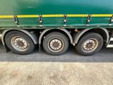a green semi truck with a yellow stripe on the side