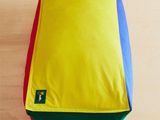 un coussin jaune, bleu, rouge et vert posé par terre