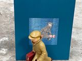 une figurine représentant un homme assis sur une valise rouge