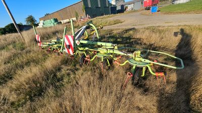 a tractor that is sitting in the grass on the side of the road