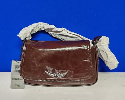 un porte-monnaie en cuir marron orné d'ailes argentées, posé sur une table
