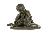 statue en bronze représentant un garçon assis sur un tapis avec un chien