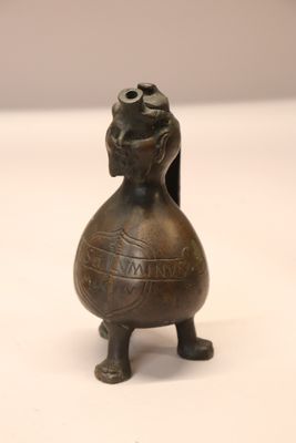 une petite figurine en bronze posée sur une surface blanche