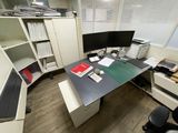 a desk with two computer monitors and a bookcase in the corner