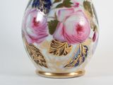 a white vase with pink and blue flowers painted on it