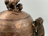 a bronze vase with a bird on top of it