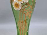 a green vase with gold and white flowers on it