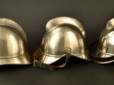 three silver helmets sitting on top of each other on a black surface