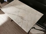 a white marble table sitting on a black leather couch