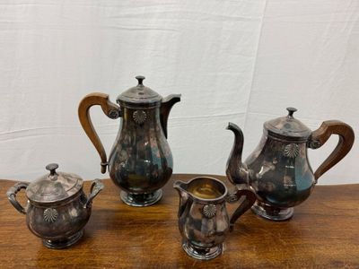 four pieces of antique silver tea and coffee set on a wooden table