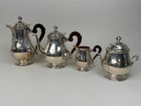 four pieces of silver tea and coffee set on a white surface