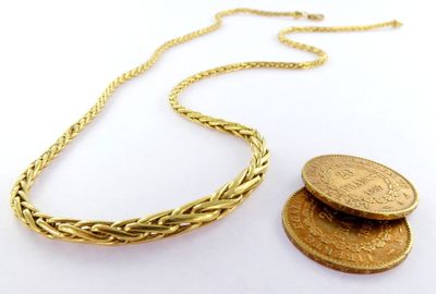 un gros plan d'une pièce de monnaie et d'un collier posés sur une surface blanche