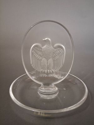 a glass bowl with an eagle on it on a plate