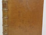 an old book with a brown cover sitting on top of a white surface