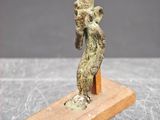 une image représentant une statue de femme tenant un oiseau sur un socle en bois
