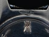 a silver clock with a bee on it ' s face