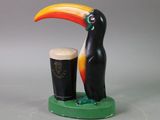 a black and yellow toucan next to a pint of guinness