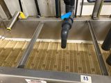 a blue pipe sticking out of the bottom of a conveyor belt