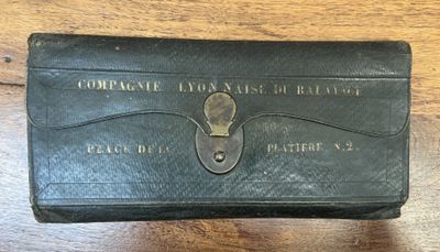 an old black leather wallet with a key on a wooden table