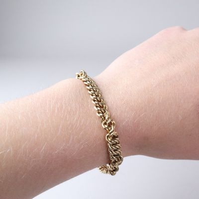 someone wearing a gold chain bracelet on their arm