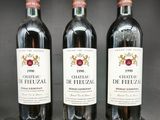 trois bouteilles de vin rouge sont posées sur un support en bois