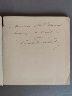un livre ouvert, sur lequel est posée une note manuscrite, posé sur une table