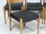 four chairs with black leather seats and a wooden frame