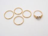 cinq bagues en or et une bague en diamant posées sur un fond blanc