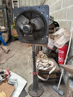 un ventilateur posé sur un support dans un garage