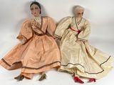 two dolls are sitting next to each other on a white surface