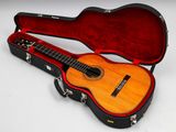 une guitare acoustique dans un étui, posée sur une surface blanche