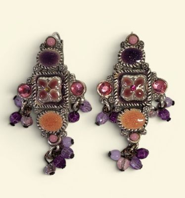 two pairs of earrings with purple and orange stones on a white surface