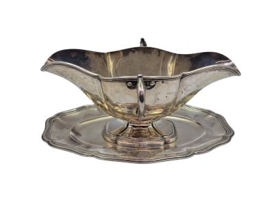 une assiette en argent ancien posée sur une soucoupe, sur fond blanc