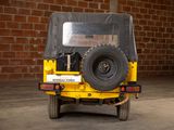 a yellow jeep parked in front of a brick wall