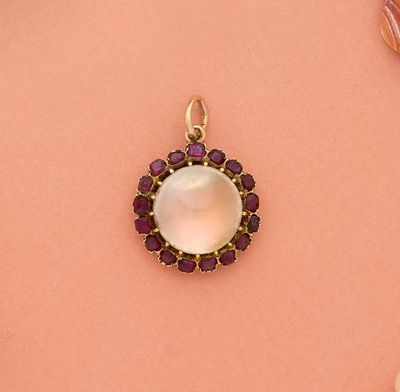 un gros plan d'un pendentif en or orné d'une pierre blanche entourée de pierres violettes
