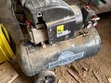 a small air compressor sitting on the ground in a garage