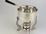 an antique silver plate with a black handle on a stand