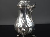une cafetière en argent posée sur une surface noire