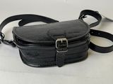 black leather cross body bag with metal buckles on a white background