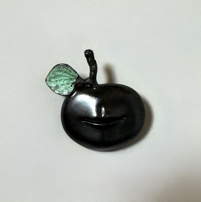 a black apple with a green leaf on top of it