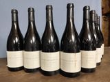 six bottles of wine are lined up on a wooden table